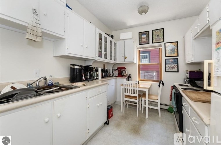 A kitchen with white cabinets and a table with chairs.
