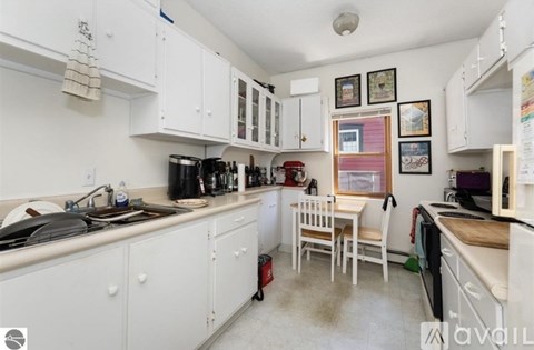 A kitchen with white cabinets and a table with chairs.
