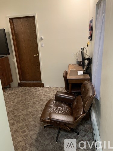 A room with a brown leather chair and a wooden desk.
