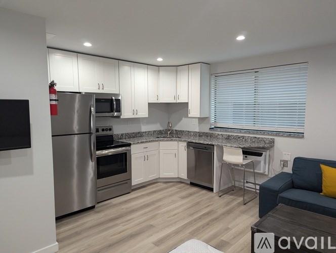 A modern kitchen with stainless steel appliances and a wooden floor.