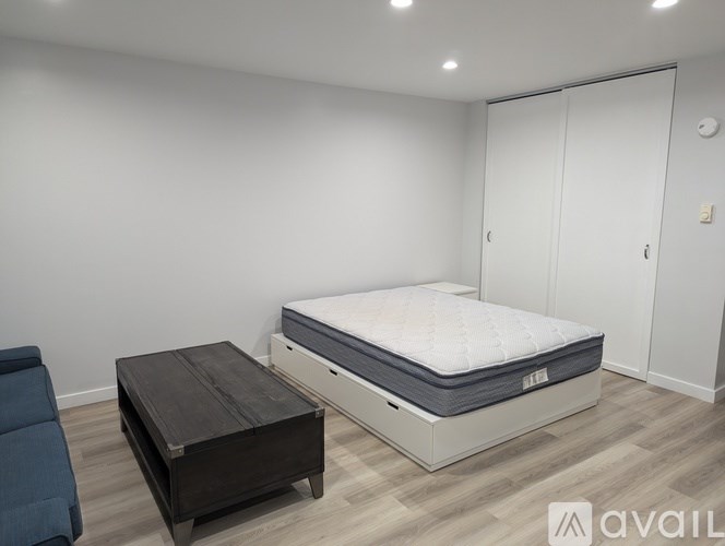 A bedroom with a bed, a mattress, and a wooden coffee table.