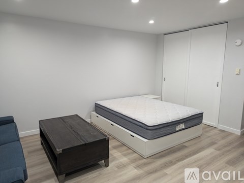 A bedroom with a bed, a mattress, and a wooden coffee table.