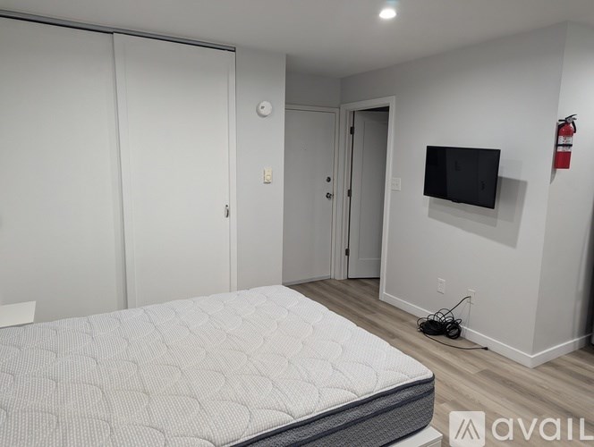 A bedroom with a bed, a television, and a fire extinguisher on the wall.