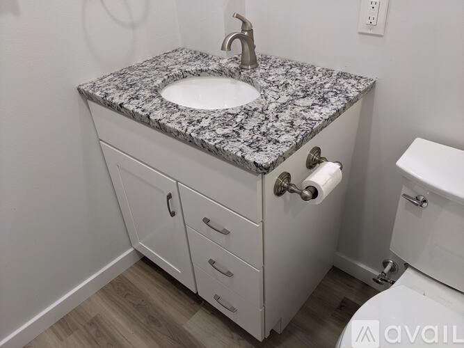 A bathroom with a granite countertop and white cabinetry.