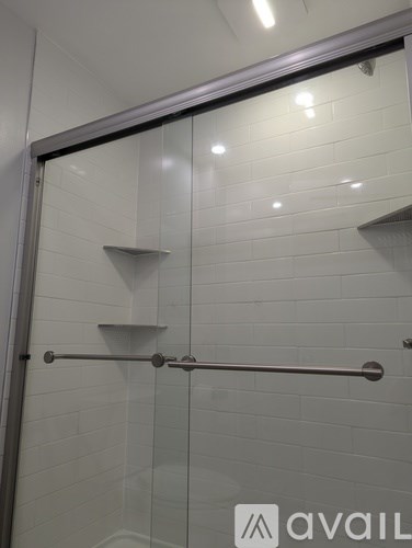 A glass shower door with a silver handle.