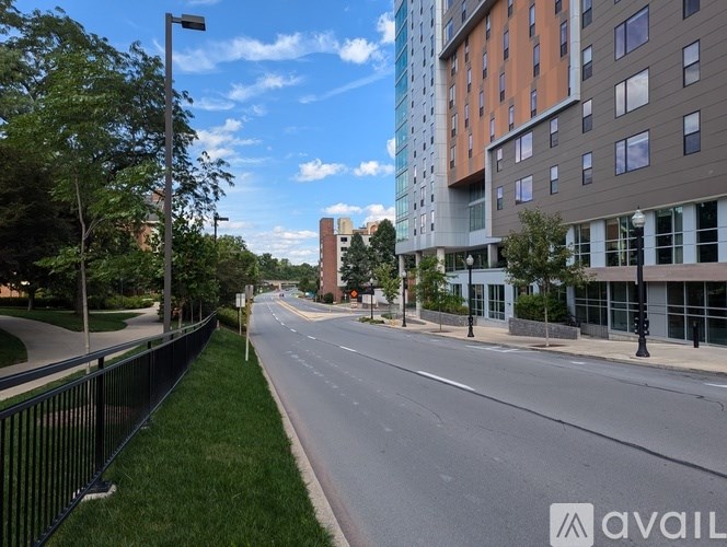 A street view with a sidewalk, a fence, and a building in the background.