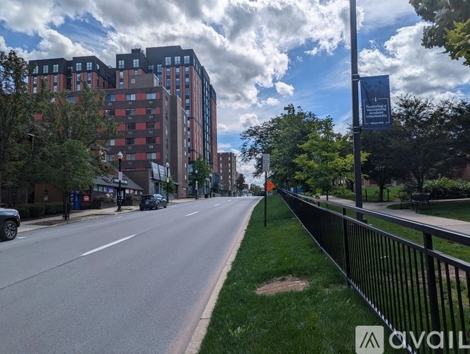 A street view with a sidewalk, cars, and apartment buildings.