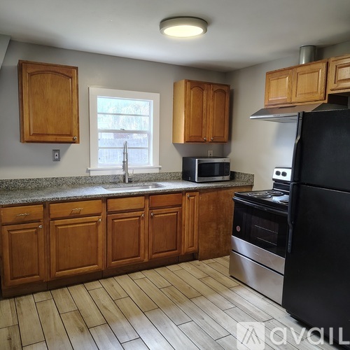 A kitchen with wooden cabinets and a window above the sink.