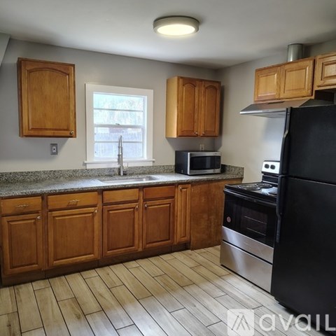 A kitchen with wooden cabinets and a window above the sink.