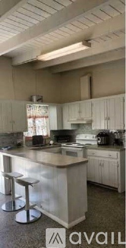 A kitchen with white cabinets and a large island with bar stools.
