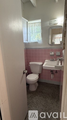 A bathroom with pink tiles and a white toilet.