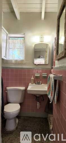 A bathroom with pink walls and a white toilet.