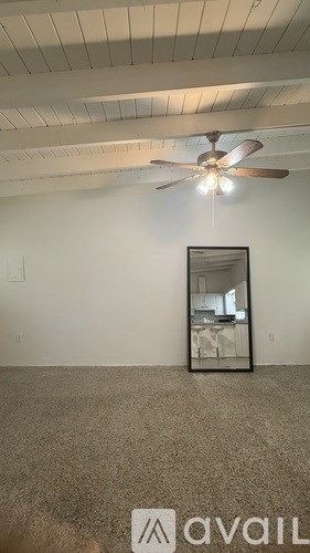 A room with a ceiling fan and a mirror on the wall.