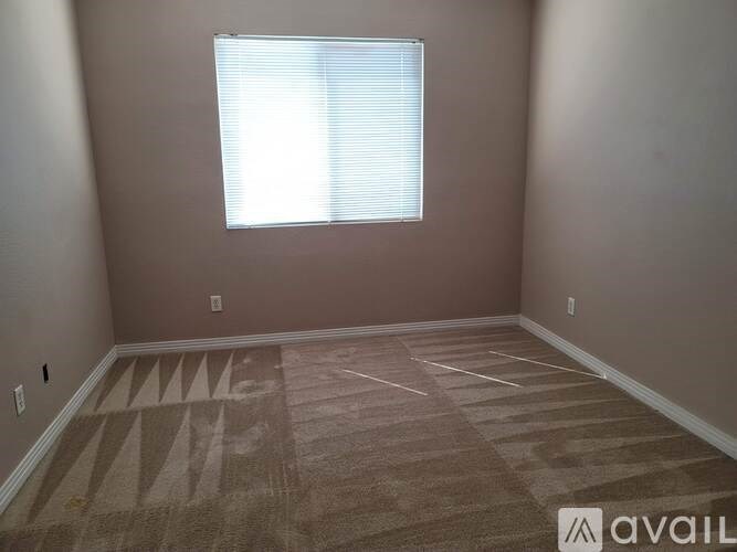A room with a carpeted floor and a window with blinds.