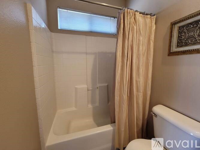 A bathroom with a white tub and a beige shower curtain.