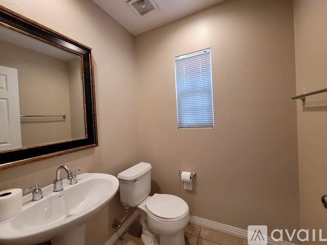 A bathroom with a toilet, sink, and mirror.