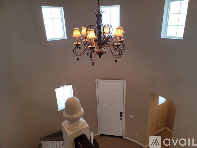 A chandelier hangs in a room with a white door and windows.