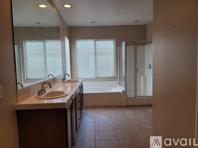 A bathroom with a large mirror, two sinks, and a bathtub.
