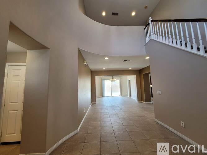 A spacious hallway with a staircase on the right and a door on the left.