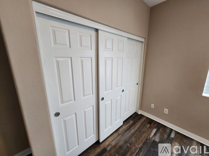 A room with a carpeted floor and two windows with blinds.