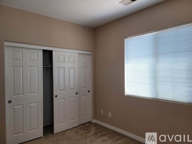A room with two white doors and a window with blinds.
