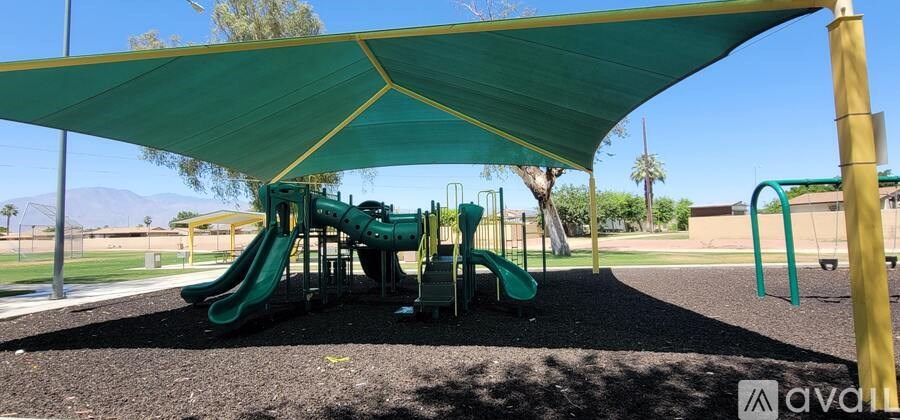 A playground with a green slide and a yellow pole.
