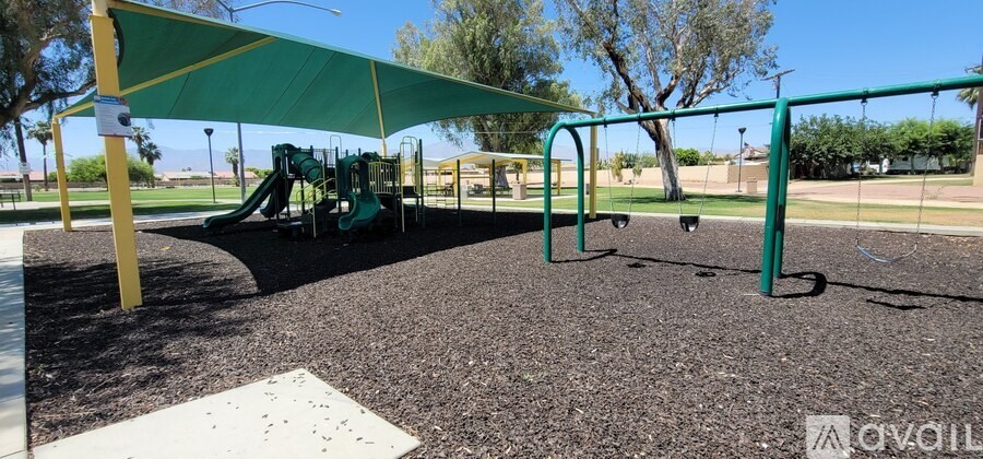 A playground with a green canopy and a slide.