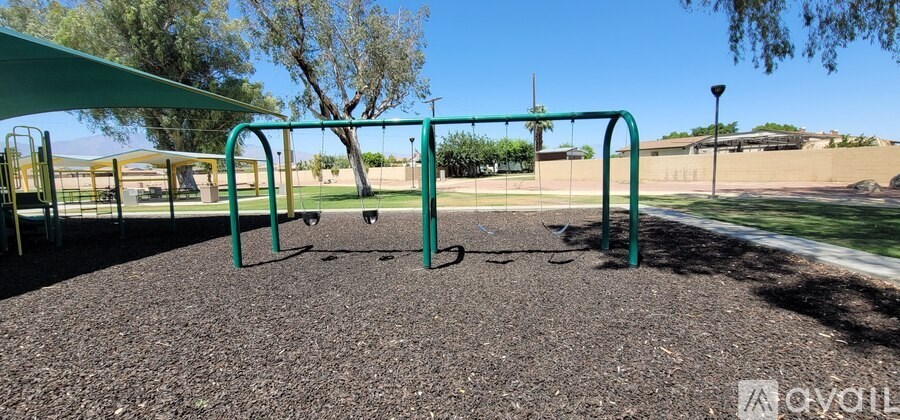 A playground with a green swing set and a shaded area.