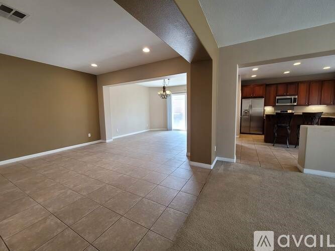 A spacious living room with a kitchen in the background.