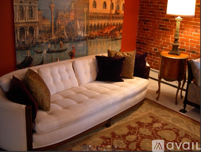 A white tufted couch with a red and gold patterned rug in front of it.