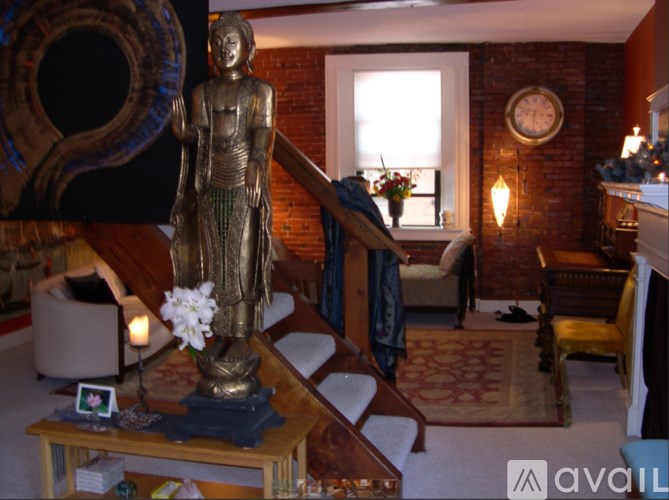 A statue of a person stands in a living room with a couch and a table.