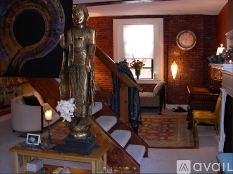 A statue of a person stands in a living room with a couch and a table.