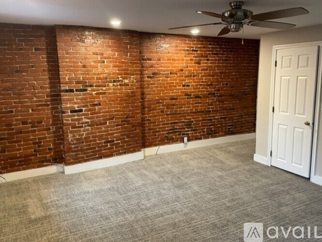 A room with a brick wall and a ceiling fan.