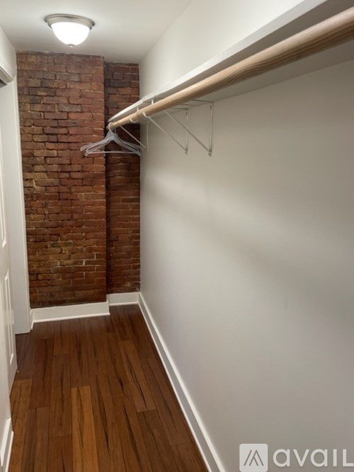 A hallway with a brick wall and a white wall with a coat rack.