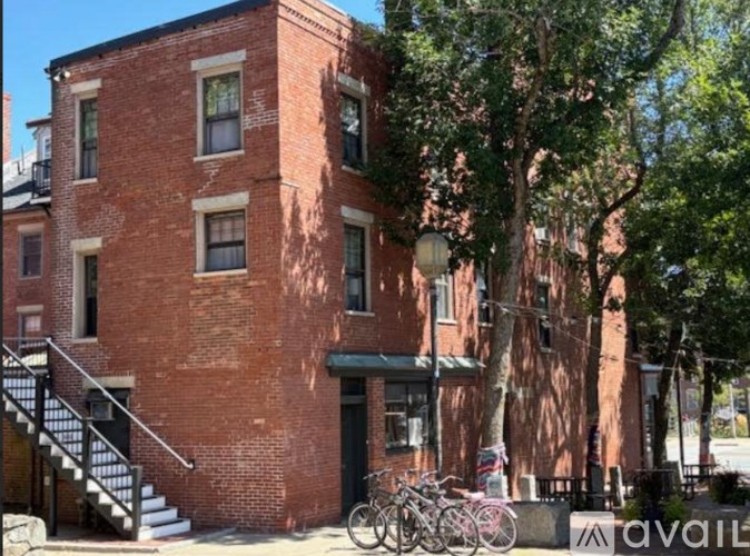A red brick building with a black awning and bicycles parked in front.