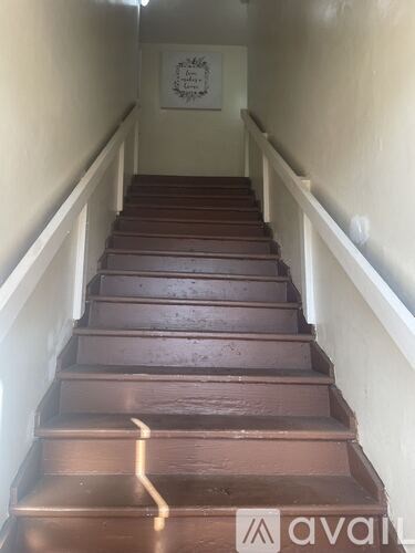 A set of stairs with a white railing and brown steps.