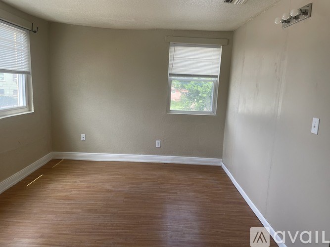 A room with wooden flooring and a window with blinds.