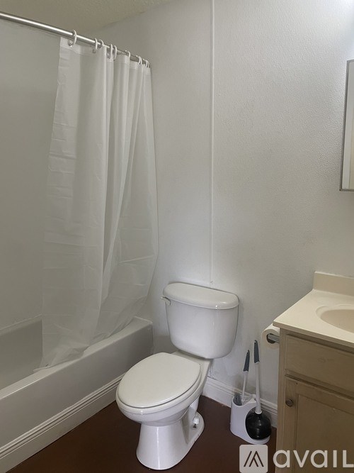 A white toilet in a bathroom with a white shower curtain.