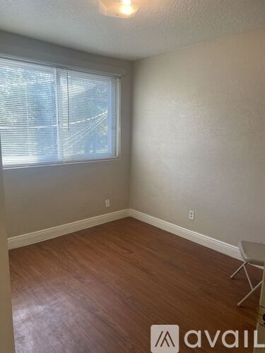 A room with a wooden floor and a window with blinds.