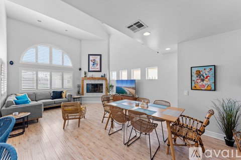 A living room with a grey couch, a fireplace, and a dining table with chairs.
