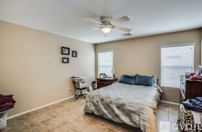 A bedroom with a bed, dresser, and ceiling fan.