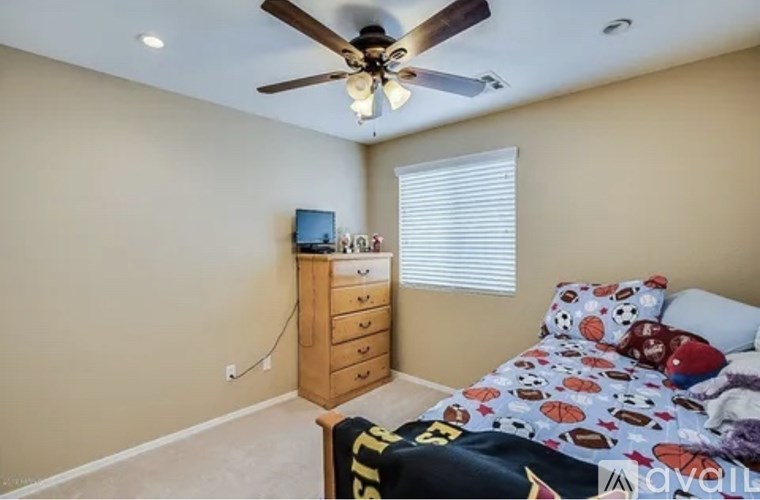 A bedroom with a bed, dresser, and ceiling fan.