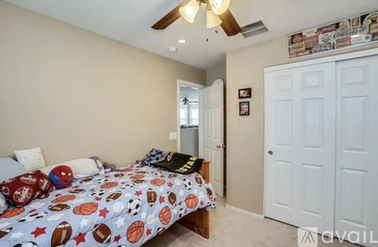 A bedroom with a bed, a ceiling fan, and a door.