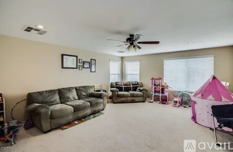 A living room with a grey couch, a pink tent, and a ceiling fan.