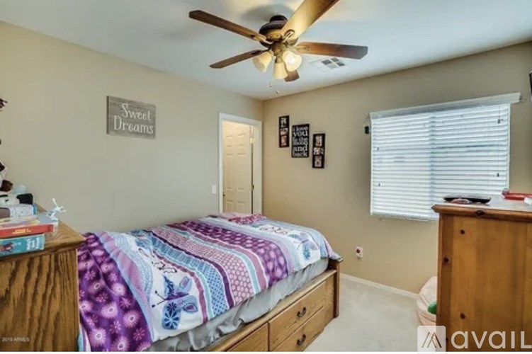 A bedroom with a bed, dresser, and a ceiling fan.