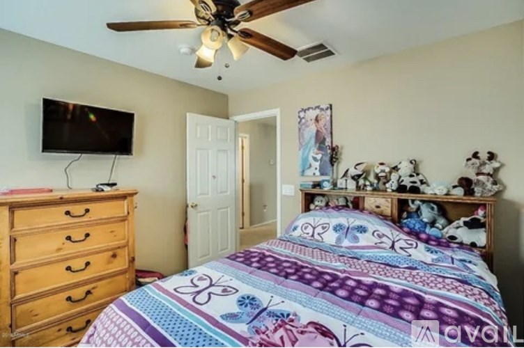 A bedroom with a bed, dresser, and a ceiling fan.