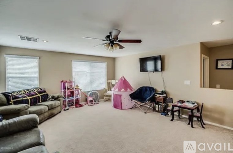 A living room with a couch, a chair, a table, a television, and a ceiling fan.