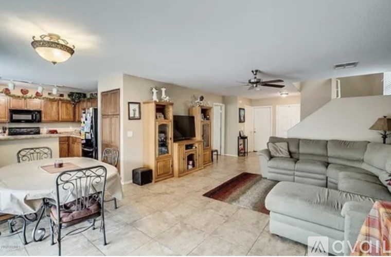 A living room with a grey couch and a dining table with chairs.