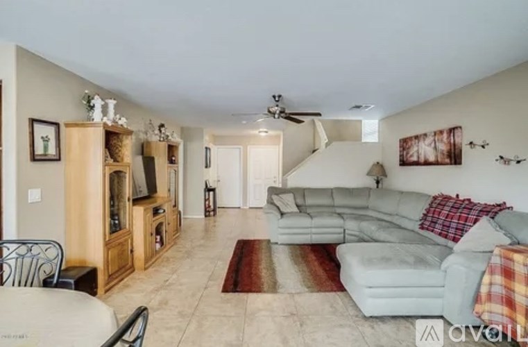 A living room with a grey couch and a red rug.