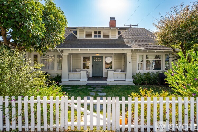 A white house with a white picket fence in front.